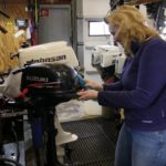 Tamara Oome poetst buitenboordmotor van de bijboot van de Calypso